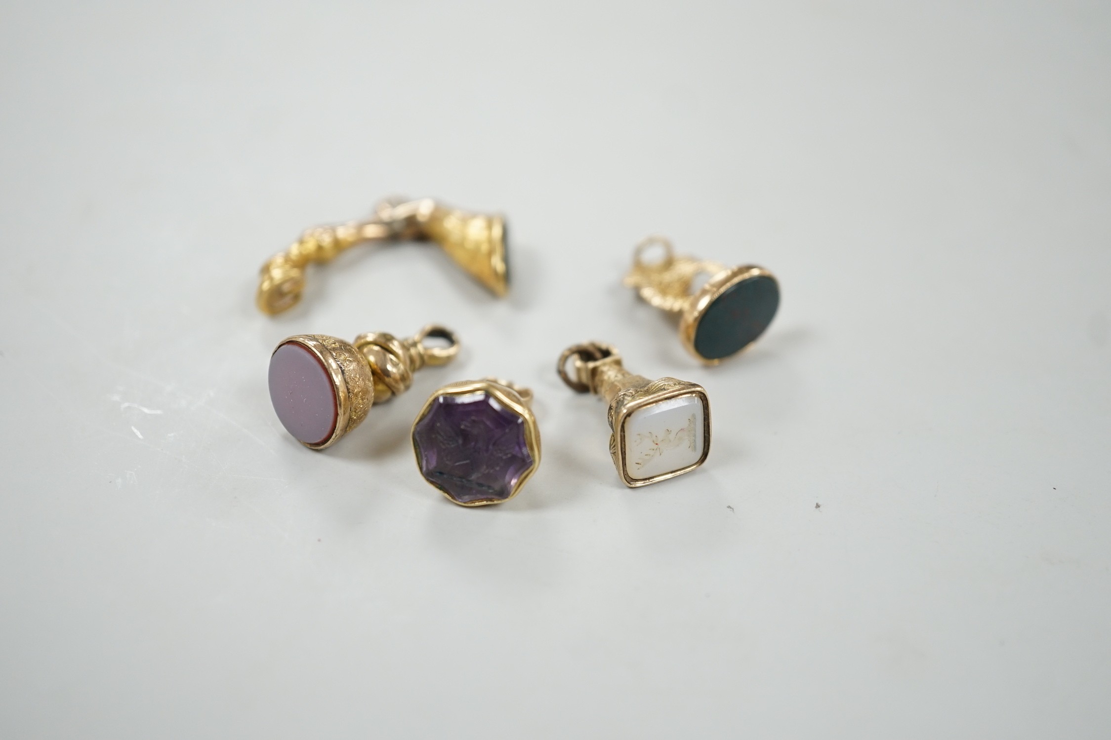 A Victorian yellow metal overlaid and bloodstone set fob seal, modelled as an entwined serpent, 22mm, two other similar fob seals set with chalcedony an a similar fob seal set with bloodstone and modelled as the leg of a